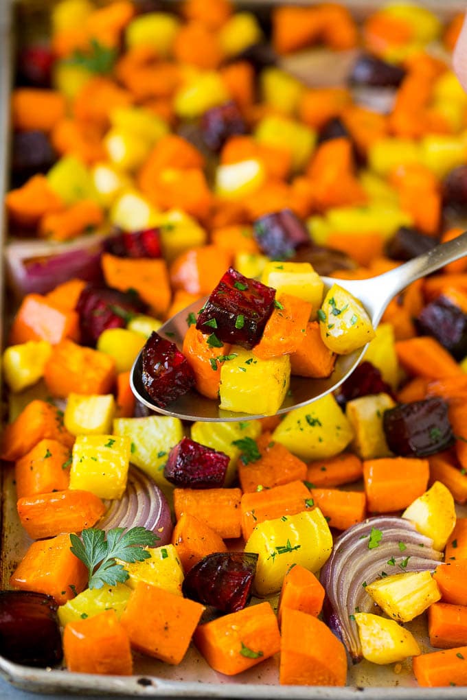 Roasted Root Vegetables Recipe | Roasted Sweet Potatoes | Roasted Beets | Roasted Carrots #carrots #beets #vegetables #sweetpotatoes #fall #parsnips #sidedish #sadud #cleaneating #healthy A spoon serving up a portion of roasted vegetables.