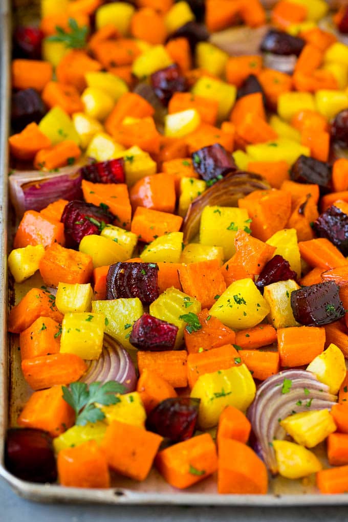 Roasted Root Vegetables Recipe | Roasted Sweet Potatoes | Roasted Beets | Roasted Carrots #carrots #beets #vegetables #sweetpotatoes #fall #parsnips #sidedish #sadud #cleaneating #healthy Roasted root vegetables on a sheet pan, topped with chopped parsley.