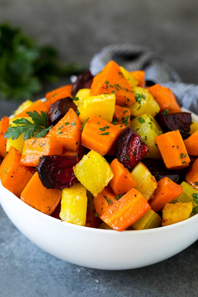 Roasted Root Vegetables Recipe | Roasted Sweet Potatoes | Roasted Beets | Roasted Carrots #carrots #beets #vegetables #sweetpotatoes #fall #parsnips #sidedish #sadud #cleaneating #healthy A bowl of diced roasted root vegetables topped with parsley.