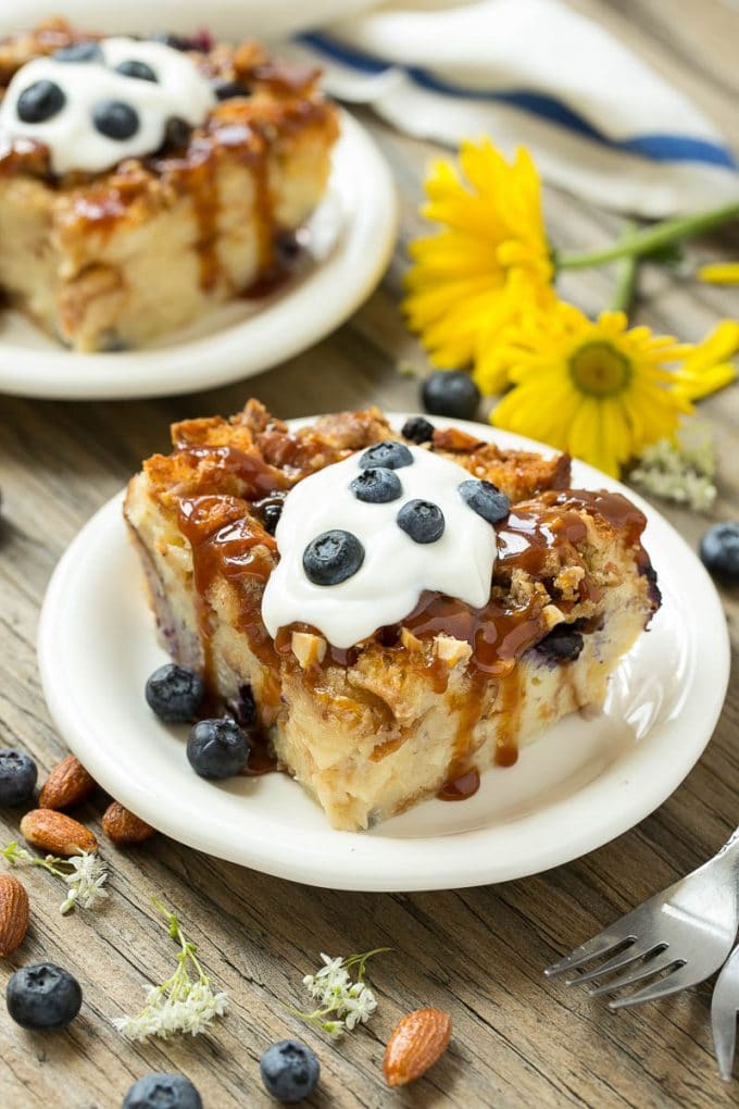 Blueberry Bread Pudding Recipe | Blueberry Bread Pudding | Easy Bread Pudding #blueberry #breadpudding #dessert #sadud Slices of bread pudding on plates, topped with caramel and fresh berries.