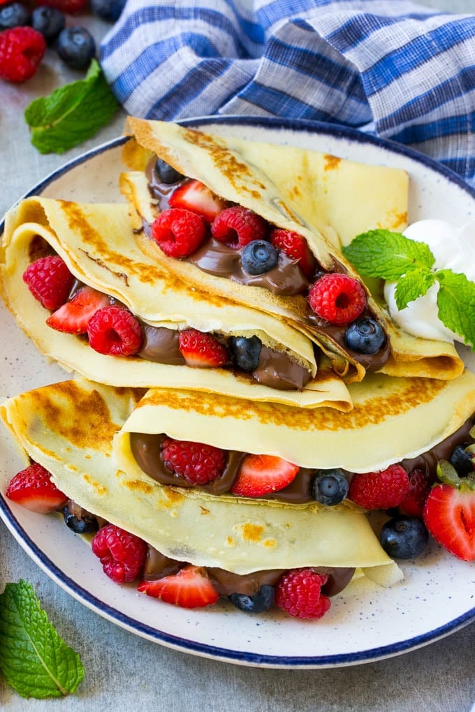 Nutella Crepes Recipe | Easy Crepes Recipe | Blender Crepes | Berry Crepes #crepes #nutella #nutellacrepes #blendercrepes #breakfast #sadud A platter of crepes served with whipped cream.