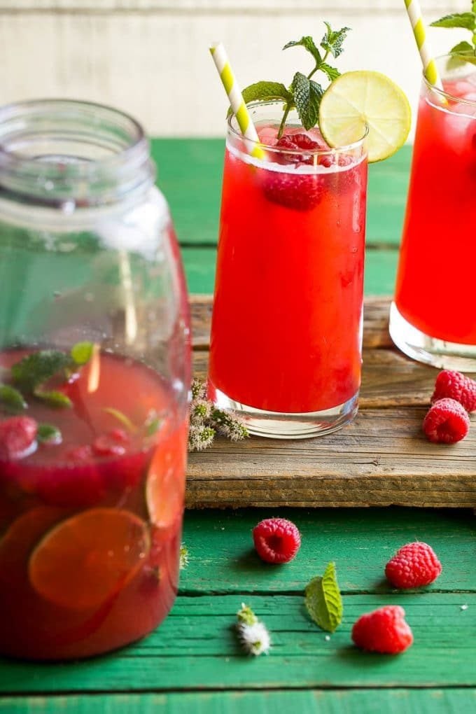 Sparkling raspberry lime drink in tall glasses with paper straws.