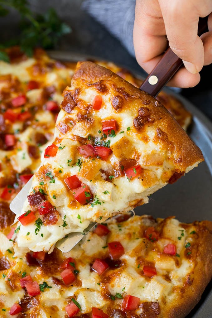 Chicken Alfredo Pizza Recipe #pizza #chicken #bacon #dinner #sadud A hand holding a spatula with a piece of chicken Alfredo pizza on it.