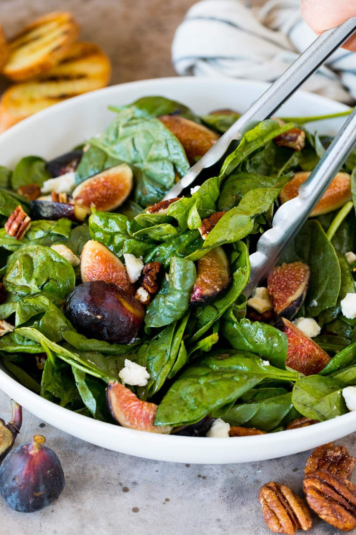 Tongs serving up a portion of fig salad.
