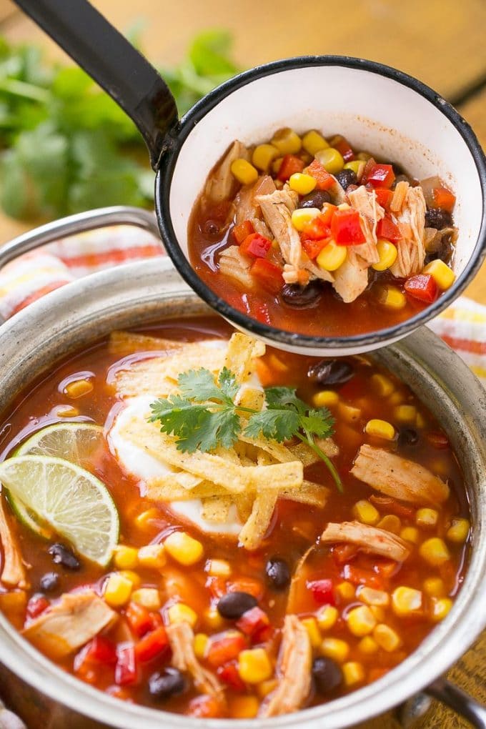 A ladle with tomatoes chicken, beans and corn ready to serve.