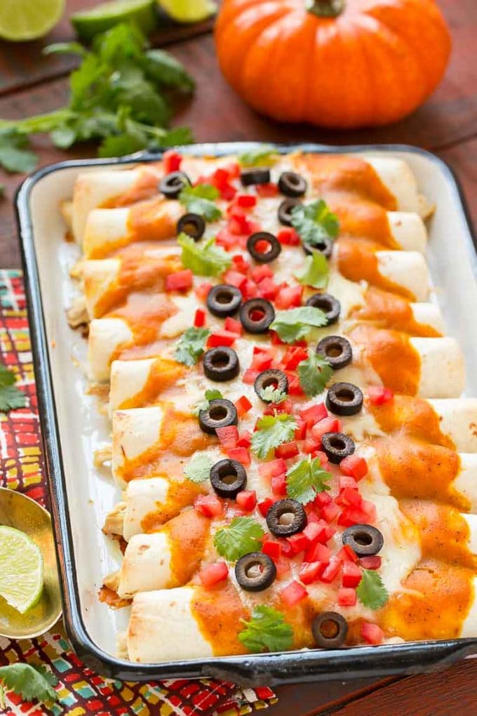A tray of pumpkin enchiladas with a creamy, savory pumpkin sauce.