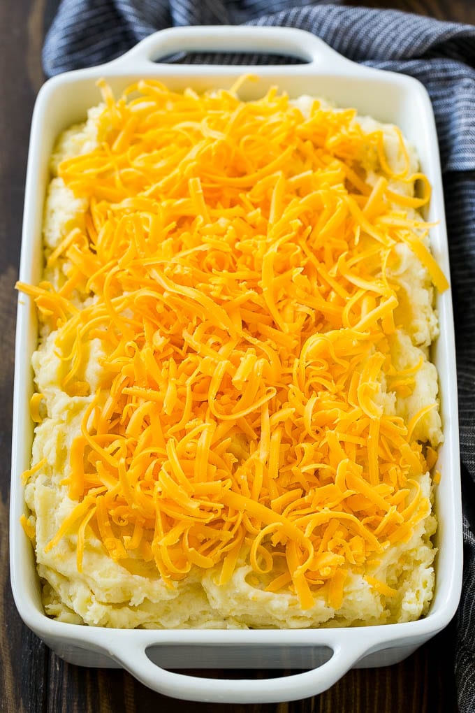 Loaded Mashed Potato Casserole Recipe | Loaded Potatoes | Bacon Mashed Potatoes | Thanksgiving Mashed Potatoes #potatoes #bacon #cheese #casserole #Thanksgiving #dinner #sadud Mashed potatoes in a casserole dish, topped with shredded cheese.