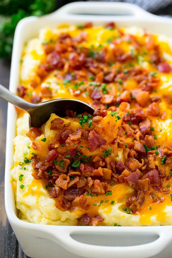 Loaded Mashed Potato Casserole Recipe | Loaded Potatoes | Bacon Mashed Potatoes | Thanksgiving Mashed Potatoes #potatoes #bacon #cheese #casserole #Thanksgiving #dinner #sadud A dish of loaded mashed potato casserole with a serving spoon in it.