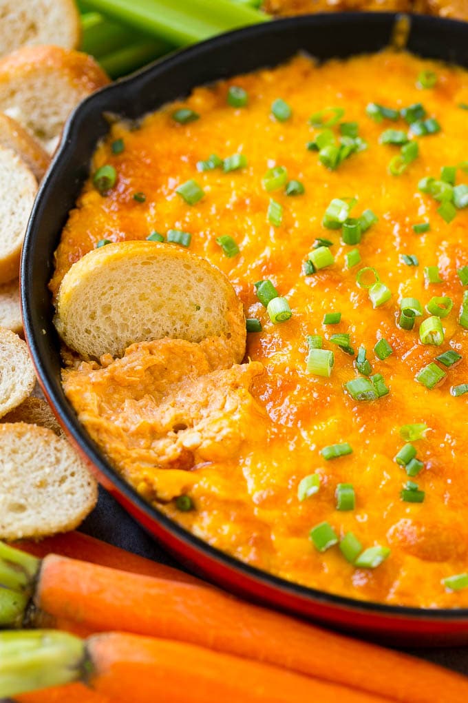 Buffalo Ranch Chicken Dip | Buffalo Chicken Dip | Baked Buffalo Dip | Cheesy Buffalo Dip #buffalowings #buffalochicken #dip #lowcarb #appetizer #sadud Buffalo ranch chicken dip with a baguette slice in it.