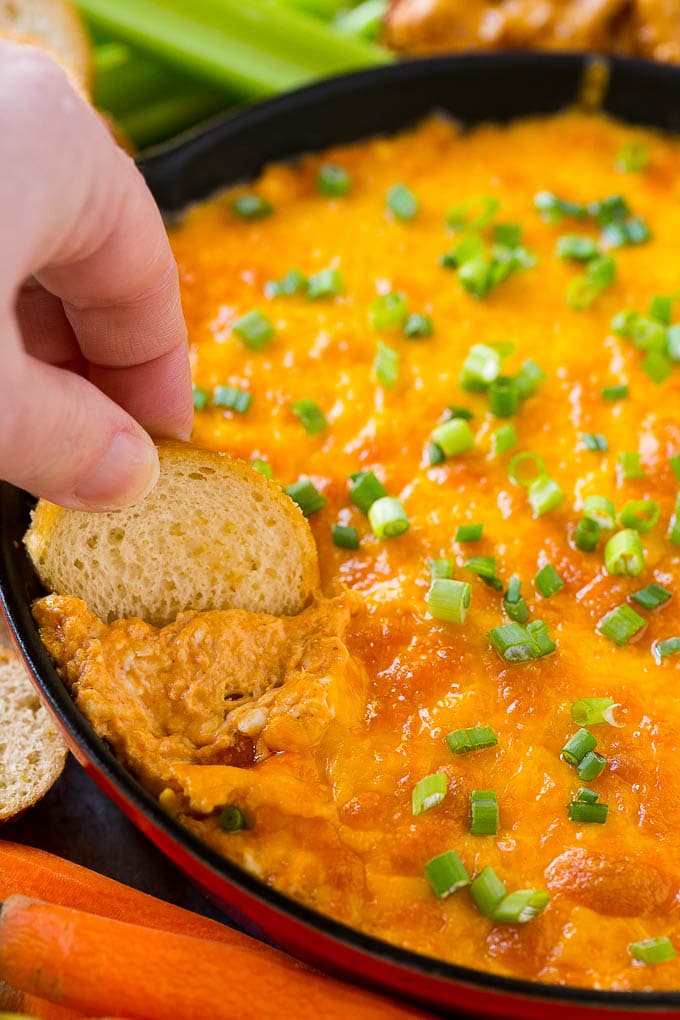 Buffalo Ranch Chicken Dip | Buffalo Chicken Dip | Baked Buffalo Dip | Cheesy Buffalo Dip #buffalowings #buffalochicken #dip #lowcarb #appetizer #sadud Baked buffalo chicken dip with a baguette slice scooping some out.