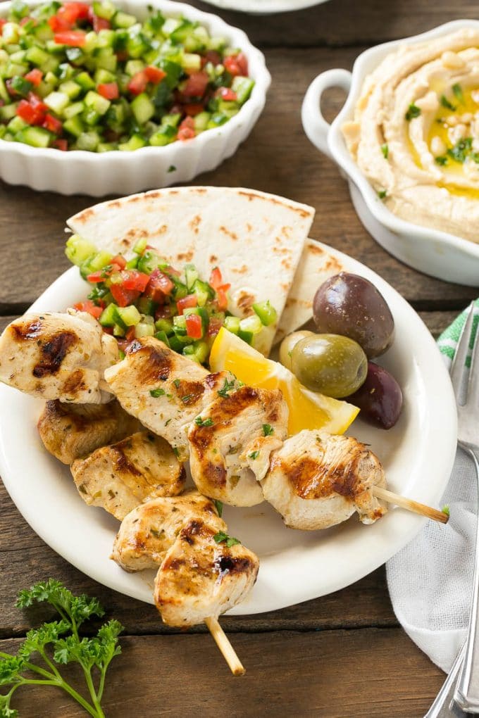 Greek Chicken Souvlaki Recipe | Easy Greek Chicken | Chicken Souvlaki | Greek Chicken Skewers | Easy Greek Chicken Skewers #chicken #kabobs #glutenfree #keto #lowcarb #grilling #sadud A plate of skewers with olives and pita bread.