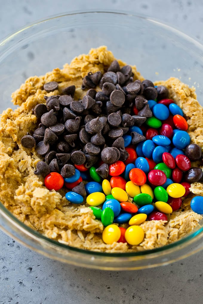 Monster Cookies Recipe | Oatmeal Cookies | Peanut Butter Cookies | M&M's Cookies #baking #cookies #dessert #peanutbutter #chocolate #sadud Cookie dough with chocolate chips and M&M's on top.