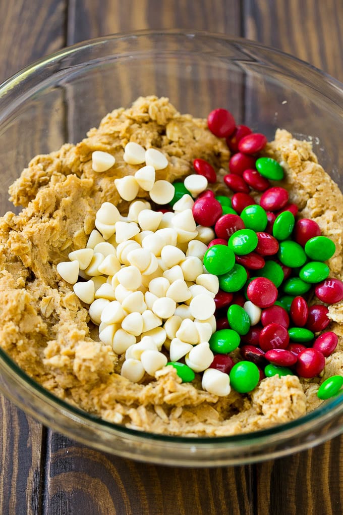 Christmas Monster Cookies Recipe | Oatmeal Cookies | Peanut Butter Cookies | M&M's Cookies #baking #cookies #dessert #peanutbutter #chocolate #sadud #christmas #sprinkles Cookie dough with red and green M&M's and white chocolate chips.