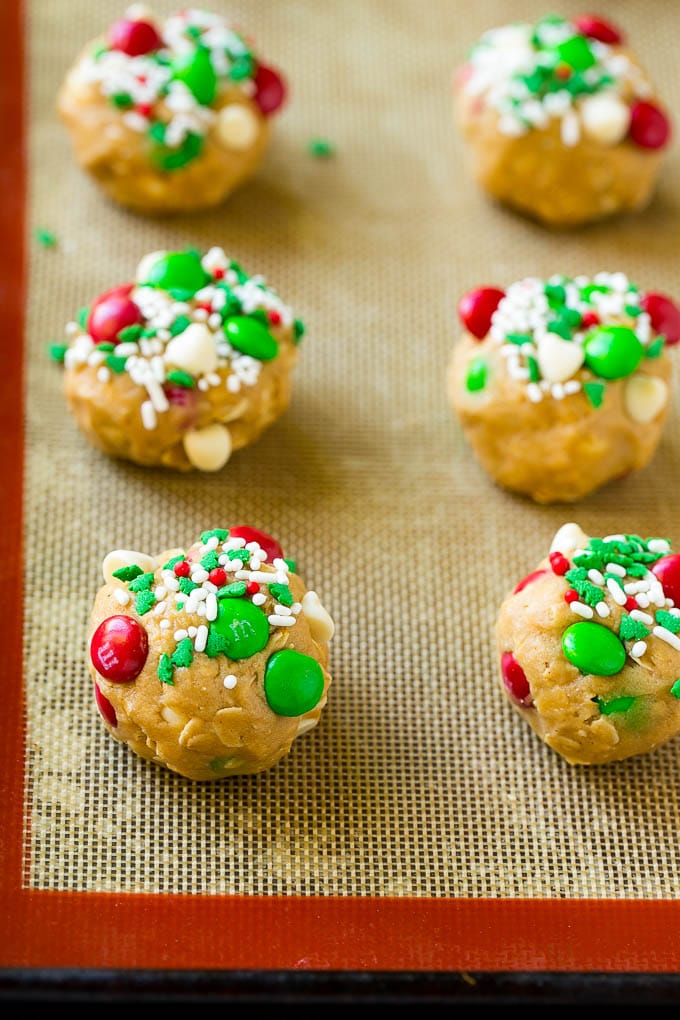 Christmas Monster Cookies Recipe | Oatmeal Cookies | Peanut Butter Cookies | M&M's Cookies #baking #cookies #dessert #peanutbutter #chocolate #sadud #christmas #sprinkles Balls of cookie dough on a baking sheet.