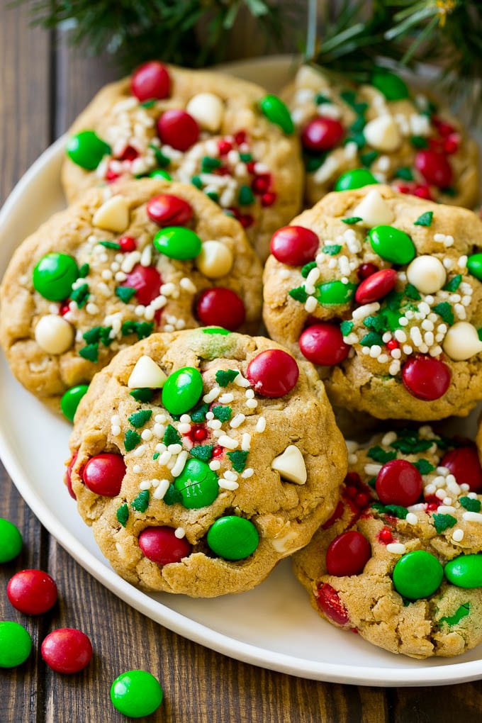 Christmas Monster Cookies Recipe | Oatmeal Cookies | Peanut Butter Cookies | M&M's Cookies #baking #cookies #dessert #peanutbutter #chocolate #sadud #christmas #sprinkles A plate of Christmas monster cookies which are decorated with M&M's, white chocolate and sprinkles.
