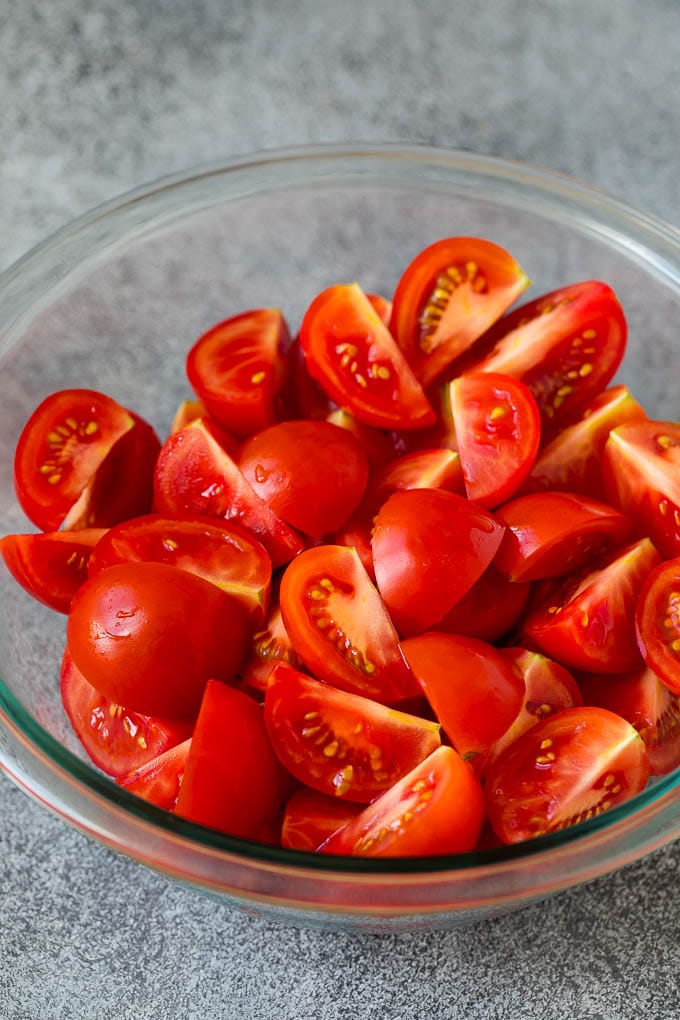 Caprese Salad Recipe | Tomato Salad #salad #tomato #mozzarella #cheese #basil #caprese #summer #sadud Quartered tomatoes in a bowl.