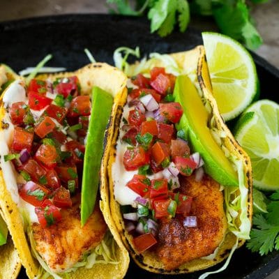 Fish tacos wrapped in corn tortillas with sliced avocado and pico de gallo.