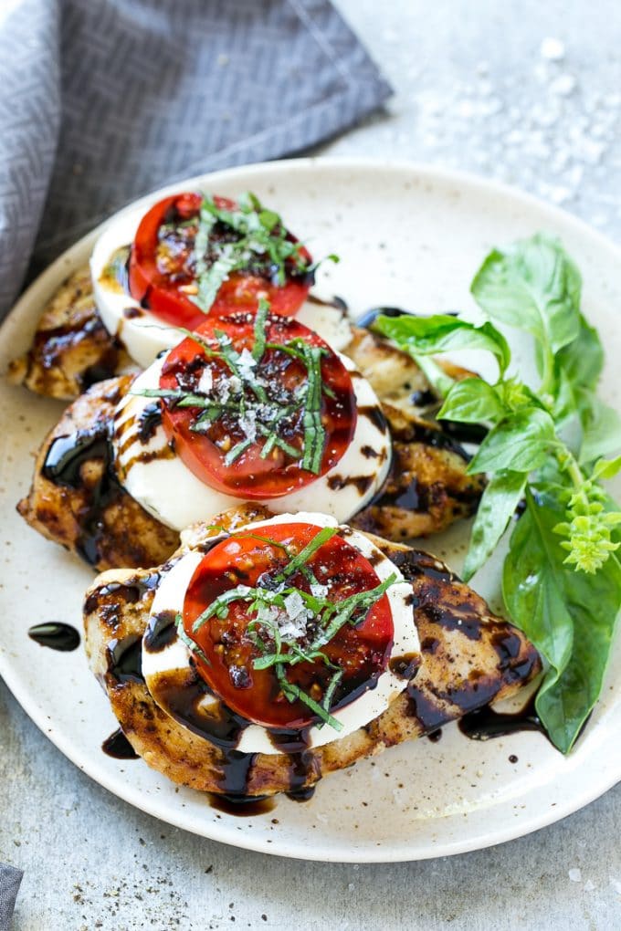 Chicken Caprese Recipe | Grilled Chicken #chicken #caprese #grilling #dinner #tomato #basil #sadud Grilled chicken on a serving plate topped with sliced tomato and cheese.