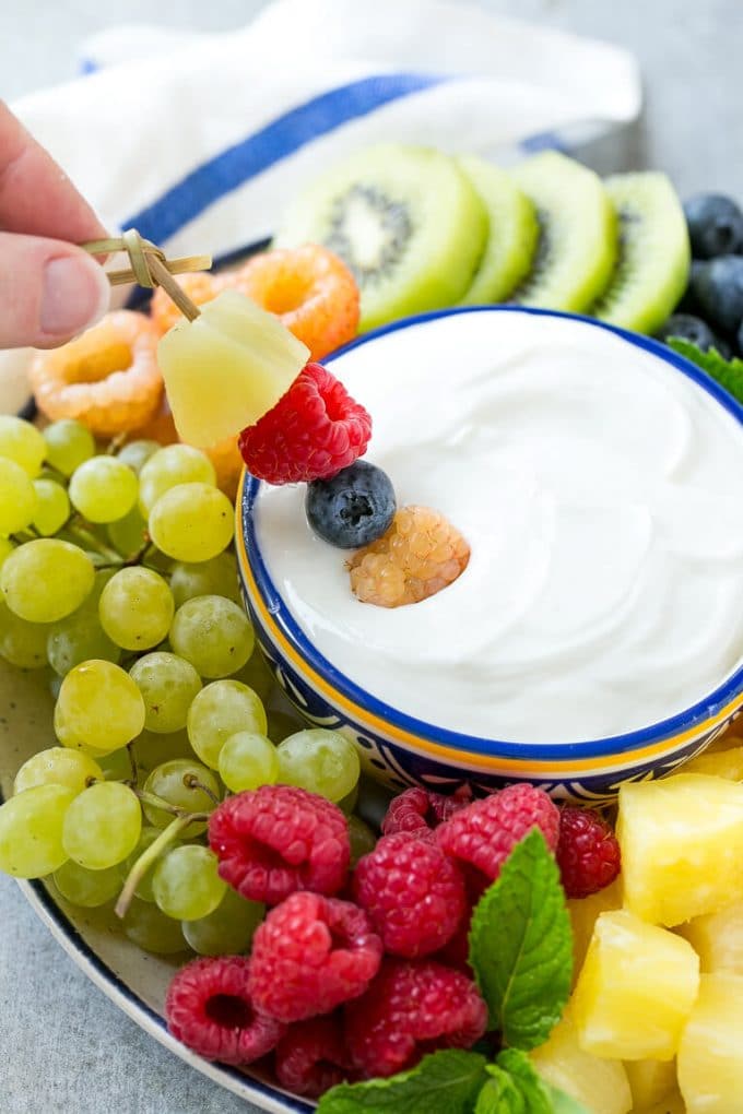 Cream Cheese Fruit Dip | Fruit Recipe | Fruit Dip #fruit #dip #creamcheese #snack #dessert #sadud A skewer of berries going into a bowl of fruit dip.