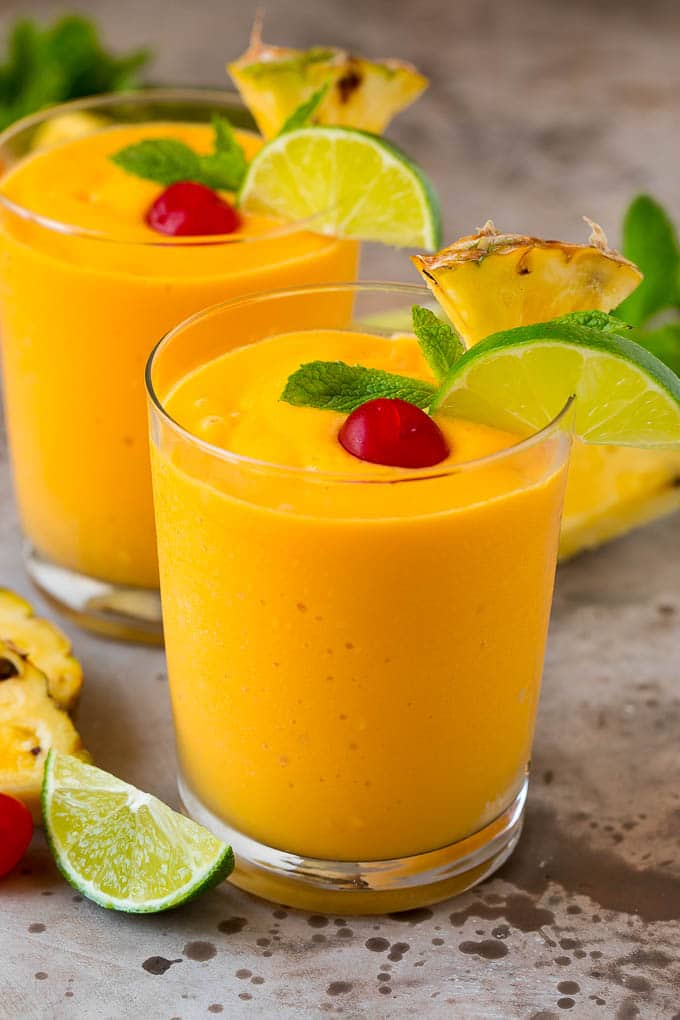 Tropical Smoothie Recipe | Mango Smoothie | Pineapple Smoothie #smoothie #mango #pineapple #banana #drink #sadud Two tropical smoothies with fresh mint, lime wedges and sliced pineapple.