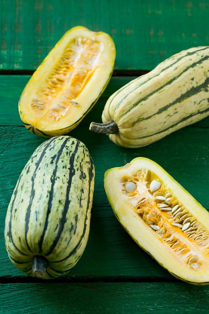 Brown Sugar Delicata Squash Recipe | Roasted Squash | Delicata Squash | Winter Squash Recipe #squash #wintersquash #brownsugar #sidedish #delicatasquash #dinner #sadud Raw delicata squash on a green board.