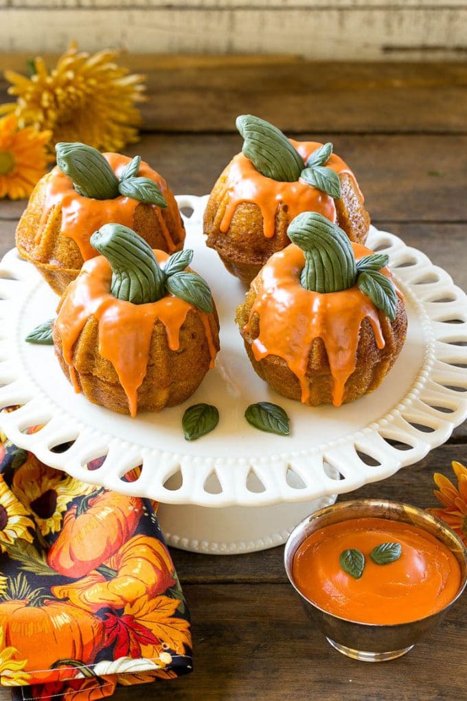 Pumpkin spice cake topped with orange glaze and fondant decorations on a serving platter.