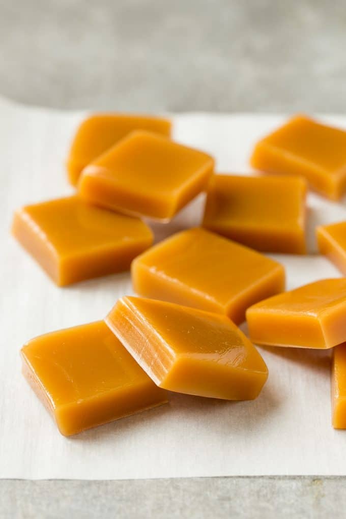 Microwave Caramels with Sea Salt Recipe | Homemade Caramels | Sea Salt Caramel | Homemade Candy #candy #caramels #caramel #microwavecaramels #homemade #dessert #sadud Squares of cooked caramel on parchment.