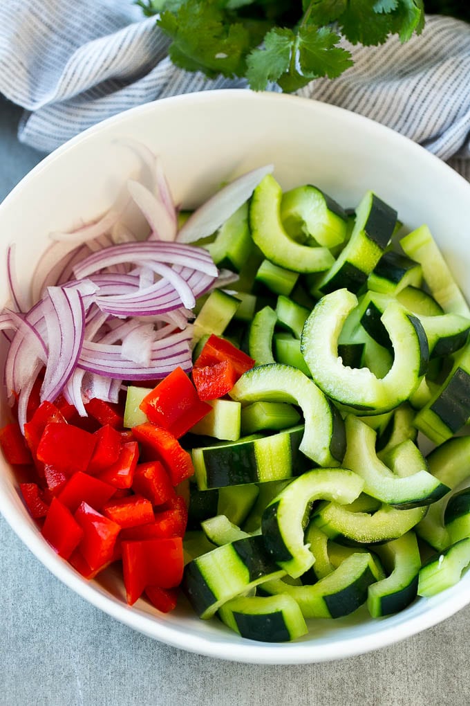 Asian Cucumber Salad Recipe | Sesame Cucumber Salad | Cucumber Salad | Healthy Salad | Healthy Cucumber Recipe #cucumber #cucumbersalad #salad #sidedish #sadud Sliced cucumbers, red peppers and red onion in a serving bowl.
