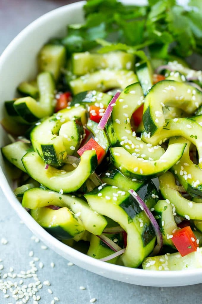 Asian Cucumber Salad Recipe | Sesame Cucumber Salad | Cucumber Salad | Healthy Salad | Healthy Cucumber Recipe #cucumber #cucumbersalad #salad #sidedish #sadud A bowl of Asian cucumber salad with dressing and sesame seeds on top.