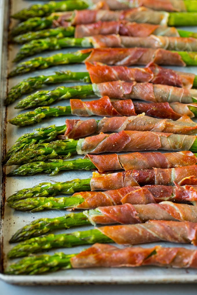 This prosciutto wrapped asparagus is fresh asparagus stalks flavored with savory prosciutto, then broiled to crispy perfection. Prosciutto wrapped asparagus on a sheet pan.