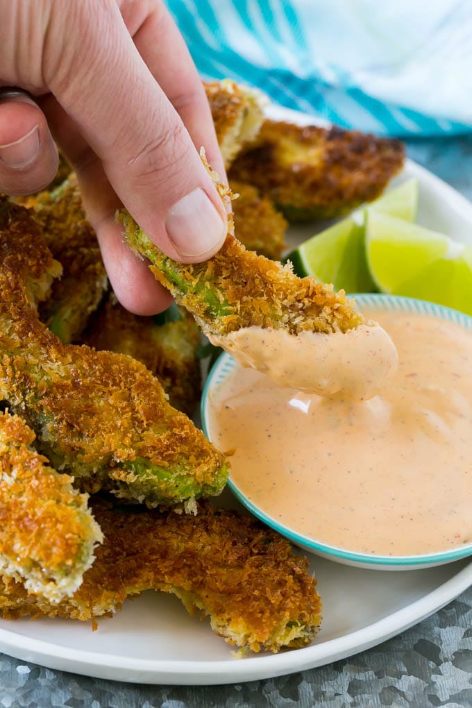 Avocado Fries Recipe | Fried Avocado | Avocado Fritters #avocado #appetizer #snack #sadud A hand dipping an avocado fry into sauce.