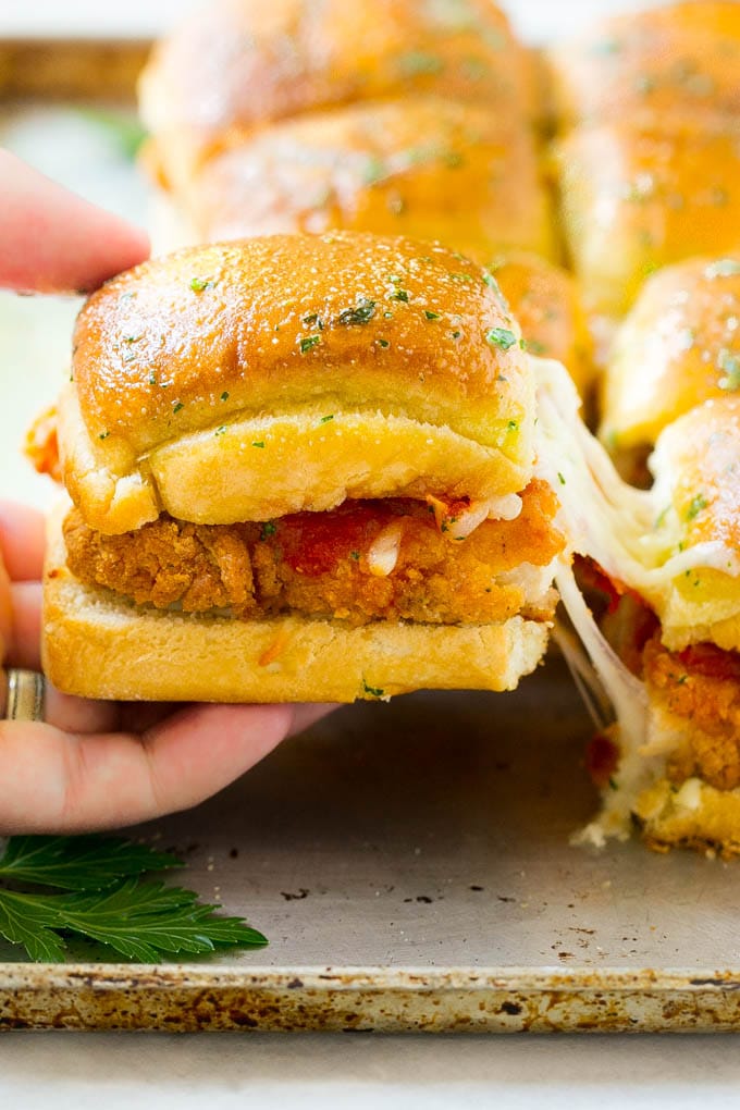 Chicken Parmesan Sliders | Chicken Parmesan Sandwich Recipe | Slider Sandwich Recipe #sliders #chickenparm #chickenparmesan #chickenparmesansliders #dinner #appetizer #sadud A crispy chicken parmesan slider being pulled away by a hand.