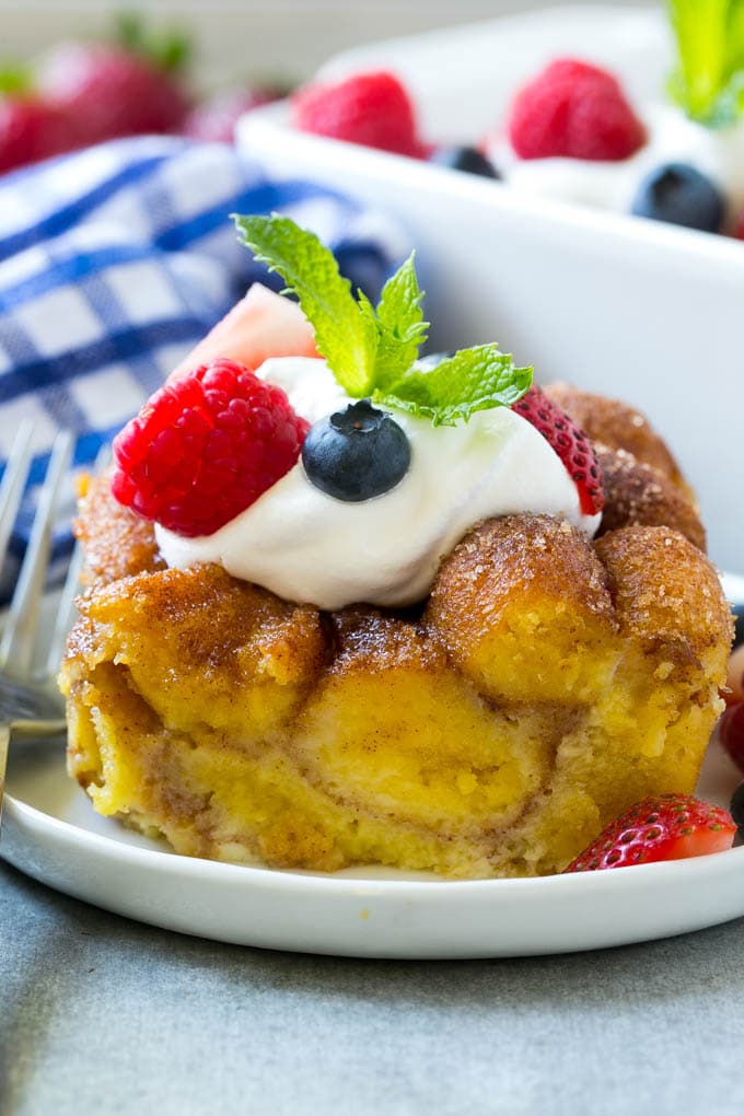 Donut Bread Pudding Recipe | Easy Bread Pudding | Cinnamon Donuts | Make Ahead Breakfast Recipe #breadpudding #donuts #donutholes #breakfast #sadud Slice of donut bread pudding topped with whipped cream and berries.