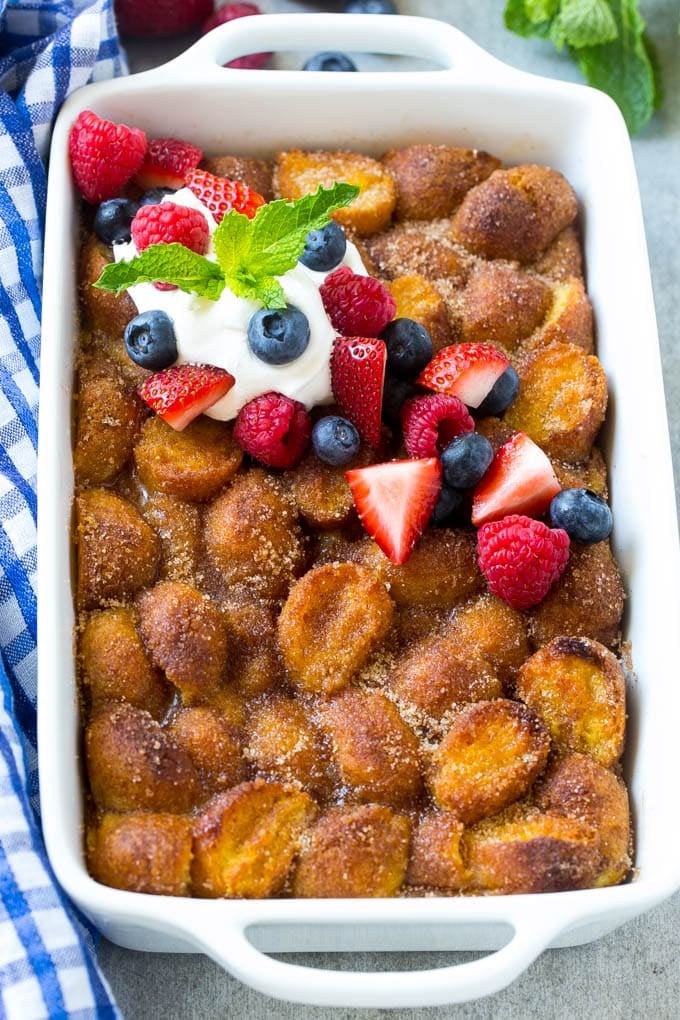 Donut Bread Pudding Recipe | Easy Bread Pudding | Cinnamon Donuts | Make Ahead Breakfast Recipe #breadpudding #donuts #donutholes #breakfast #sadud A tray of donut bread pudding garnished with whipped cream and berries.