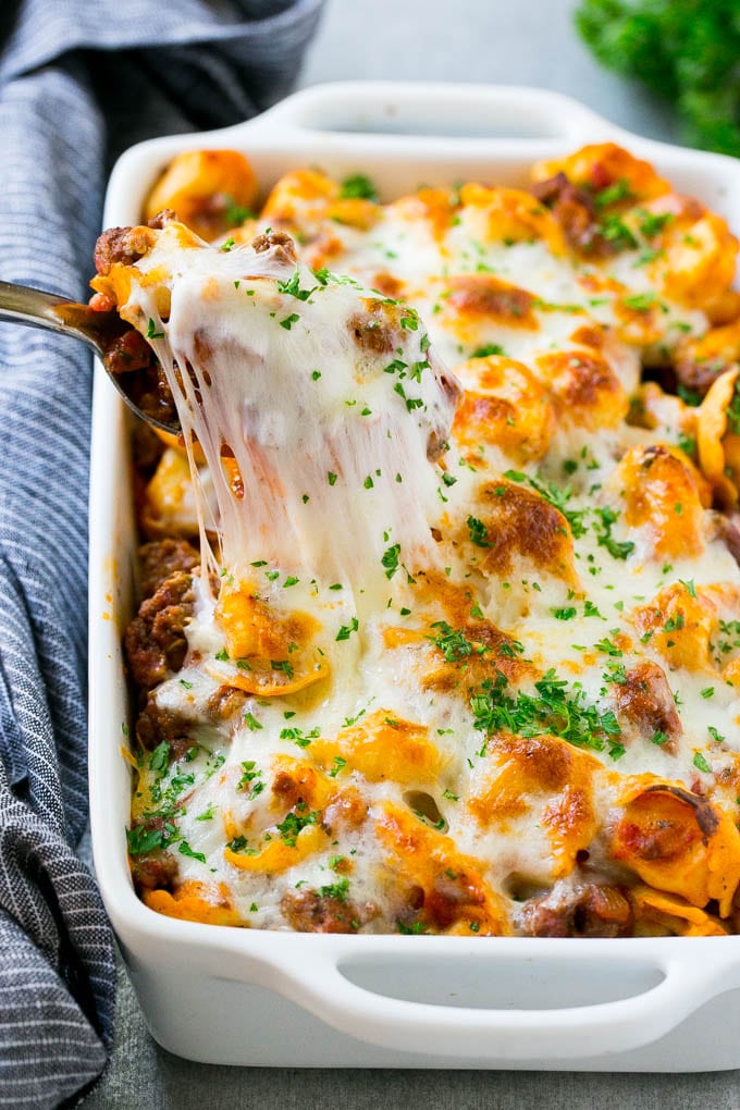 Baked Tortellini with Meat Sauce Recipe | Cheese Tortellini | Tortellini Recipe | Baked Pasta Recipe #tortellini #bakedtortellini #meatsauce #pasta #dinner #sadud A pan of cheesy baked tortellini with a spoon lifting up a portion.