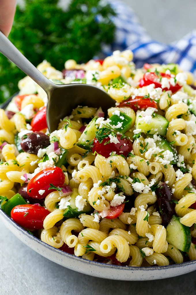 Greek Pasta Salad | Easy Pasta Salad | Vegetable Pasta Salad #pasta #salad #greek #cucumber #tomato #vegetarian #dinner #sadud A bowl of Greek pasta salad with a serving spoon in it.