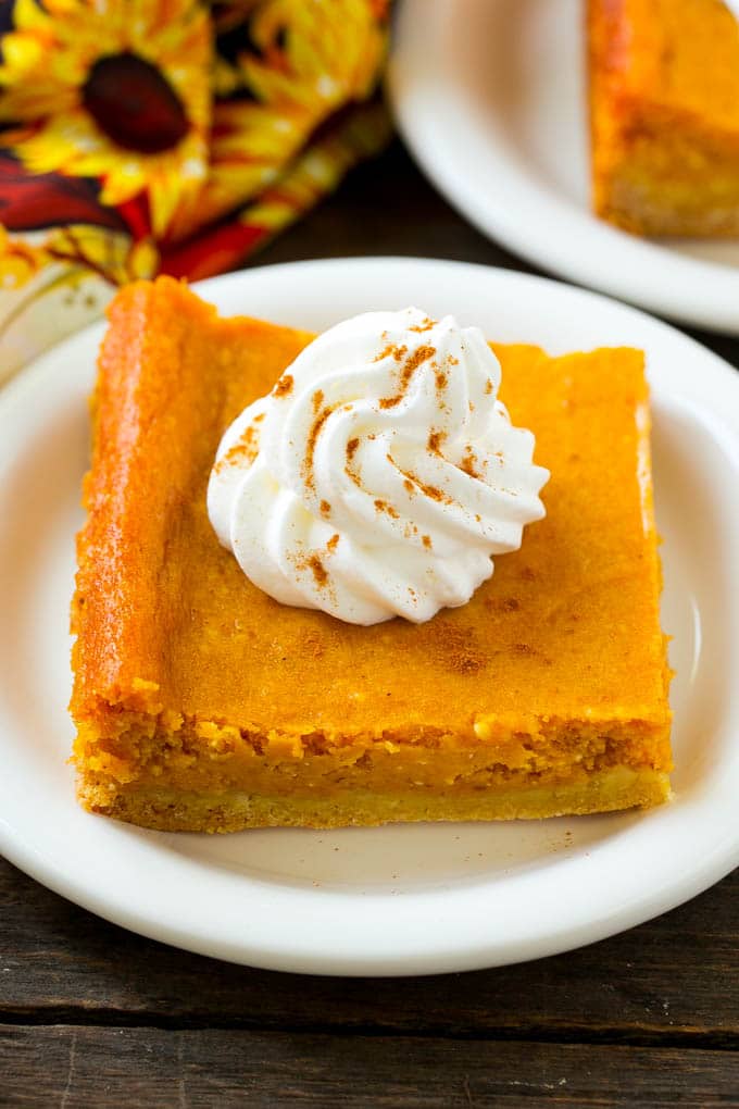 Pumpkin Gooey Butter Cake Recipe | Pumpkin Cake Recipe | Gooey Butter Cake | Pumpkin Dessert | Thanksgiving Dessert #pumpkin #cake #pumpkincake #gooeybuttercake #dessert #sadud A slice of pumpkin gooey butter cake topped with whipped cream.
