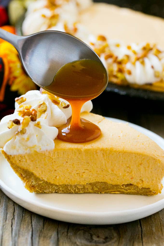 No Bake Pumpkin Cheesecake Recipe | Pumpkin Cheesecake | No Bake Cheesecake | Thanksgiving Dessert | Pumpkin Dessert #nobake #cheesecake #pumpkin #pumpkinpie #pumpkincheesecake #nobakecheesecake #dessert #sadud A spoon pouring caramel over a slice of pumpkin cheesecake.
