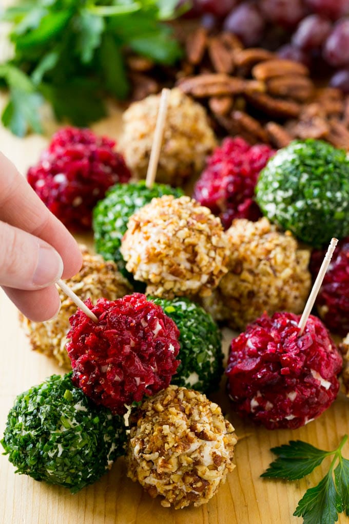 Cheese Ball Bites Recipe | Holiday Cheese Ball Recipe | Pecan Cheese Ball | Cranberry Cheese Ball | Mini Cheese Balls #cheeseball #cheese #appetizer #sadud A hand reaching for an appetizer crusted in dried craberries.