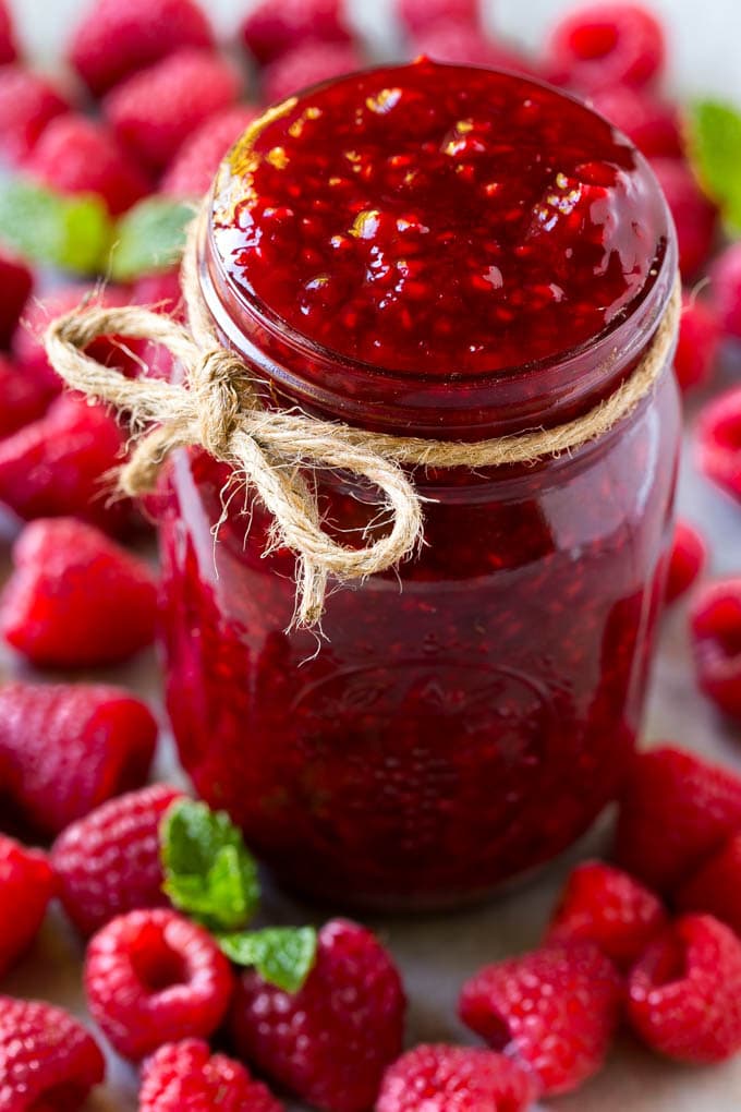 Raspberry Sauce Recipe | Homemade Raspberry Sauce | Raspberry Recipe #raspberries #dessert #sadud A jar of homemade raspberry sauce surrounded by fresh raspberries.