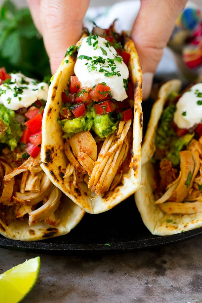 A hand picking up a slow cooker chicken taco.