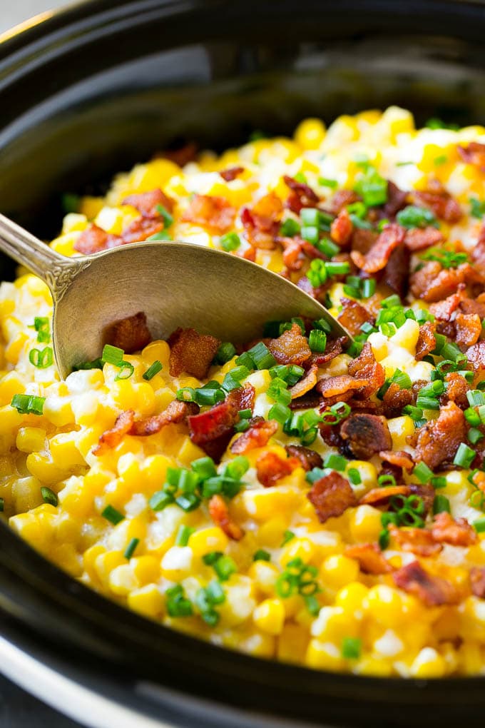 Slow Cooker Creamed Corn Recipe | Easy Creamed Corn Recipe | Slow Cooker Creamed Corn with Bacon | Southern Creamed Corn | Creamed Corn with Cream Cheese #creamedcorn #corn #bacon #crockpot #slowcooker #dinner #sadud A serving spoon in a crock pot full of creamed corn.