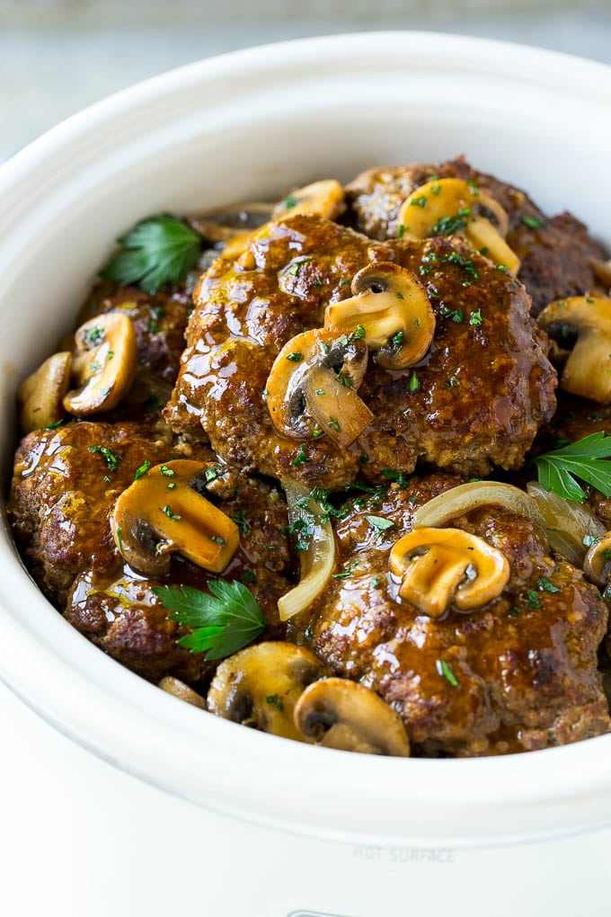 Slow Cooker Salisbury Steak Recipe | Homemade Salisbury Steak | Salisbury Steak from Scratch #steak #beef #salisbury #salisburysteak #slowcooker #crockpot #dinner #sadud A crock pot with hamburger patties, cooked mushrooms and gravy.