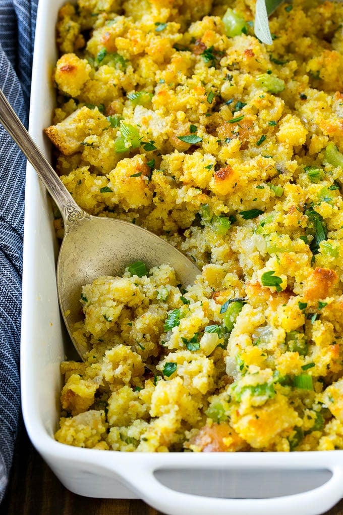 This old fashioned Southern cornbread dressing recipe is a classic that's a must-have for every Thanksgiving table. It's made with celery, onions, homemade cornbread, white bread and plenty of herbs. Cornbread dressing made with cornbread, white bread and vegetables, with a serving spoon in it.