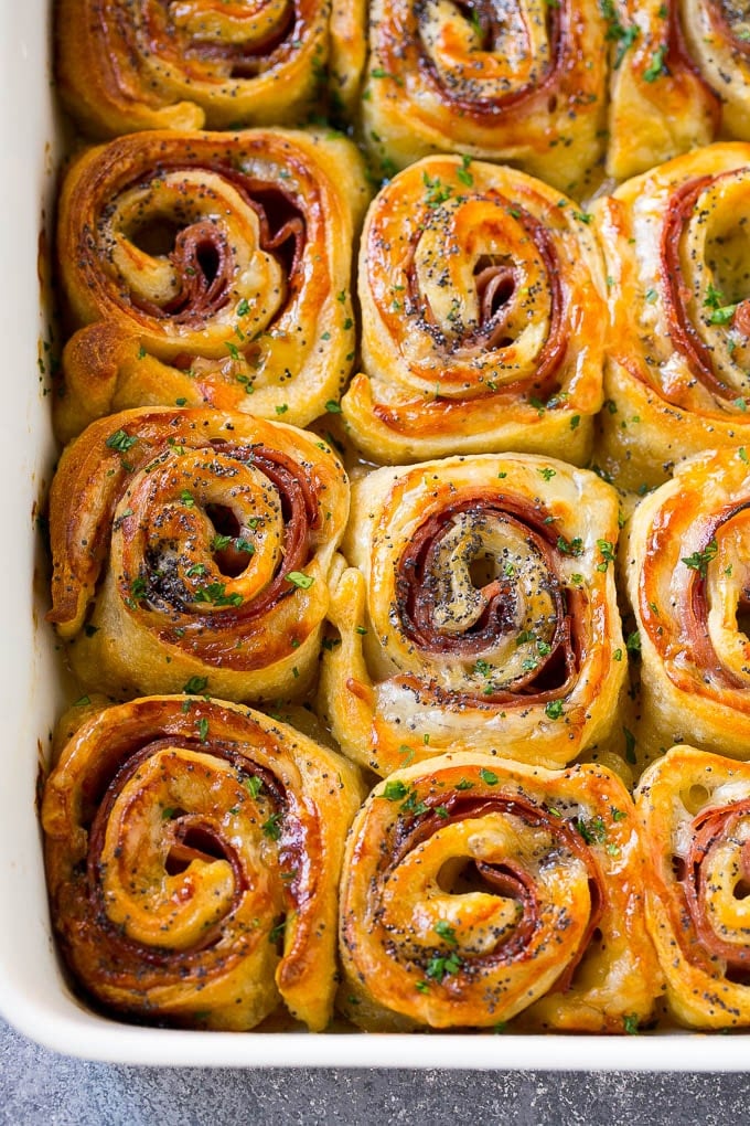Ham and Cheese Pinwheels Recipe | Ham and Cheese Roll Ups | Ham and Cheese Rolls | Ham and Cheese Bread Rolls #ham #cheese #appetizer #pinwheels #sadud Ham and cheese pinwheels in a baking dish topped with parsley.