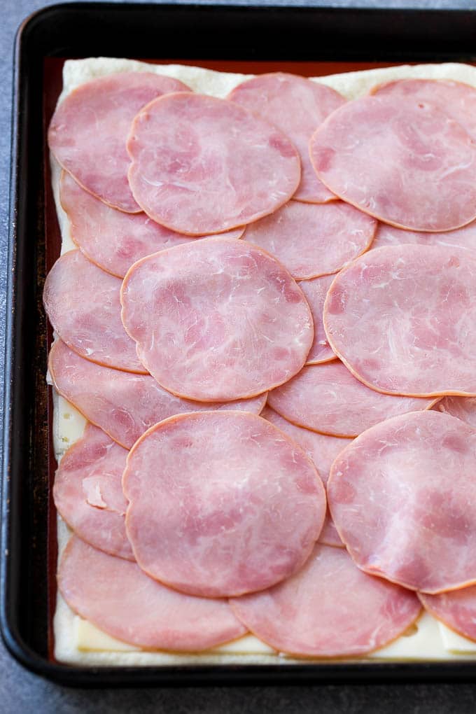 Ham and Cheese Pinwheels Recipe | Ham and Cheese Roll Ups | Ham and Cheese Rolls | Ham and Cheese Bread Rolls #ham #cheese #appetizer #pinwheels #sadud Slices of ham and cheese on top of dough.