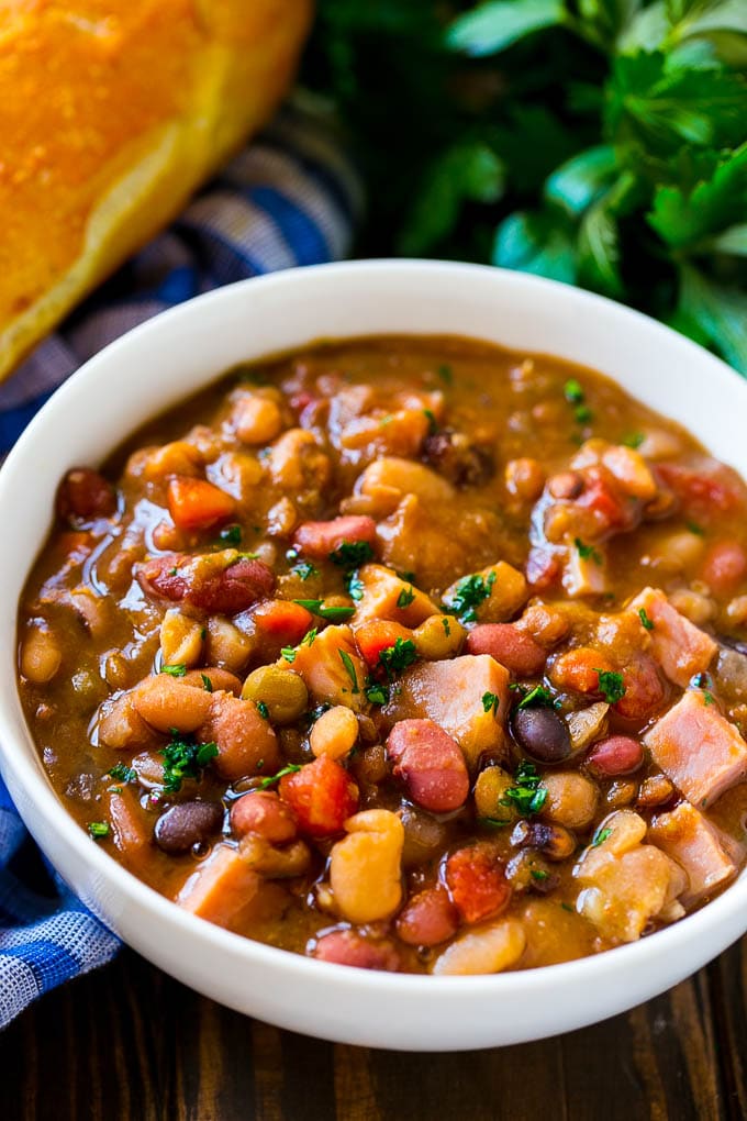 Slow Cooker Ham Bone Soup | Ham and Bean Soup | Ham Bone and Bean Soup | Ham Soup | Leftover Ham Recipe #ham #hamsoup #leftoverham #soup #slowcooker #crockpot #sadud Crock pot ham bone soup in a bowl topped with parsley.