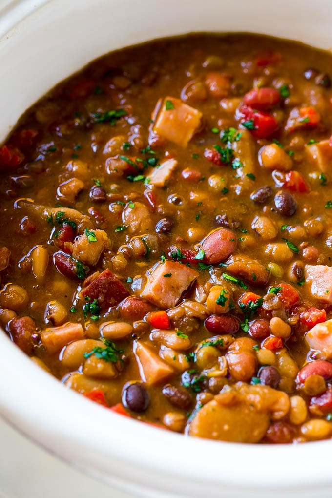 Slow Cooker Ham Bone Soup | Ham and Bean Soup | Ham Bone and Bean Soup | Ham Soup | Leftover Ham Recipe #ham #hamsoup #leftoverham #soup #slowcooker #crockpot #sadud A slow cooker full of soup with parsley on top.