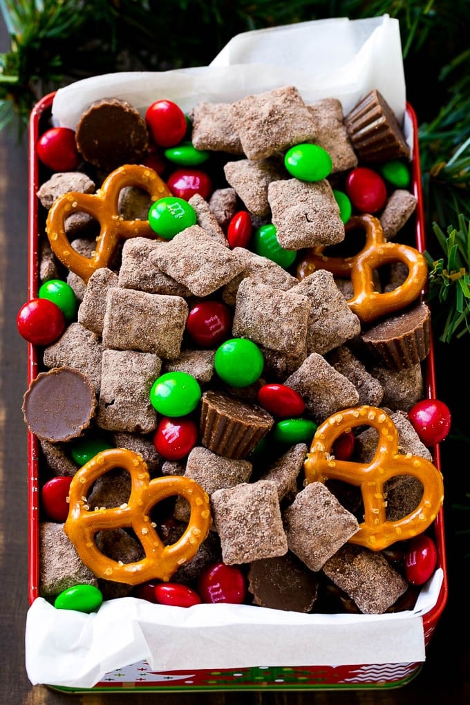 Reindeer Chow | Christmas Chex Mix | Christmas Muddy Buddies | Holiday Chex Mix #chex #chexmix #christmas #holiday #muddybuddies #reindeerchow #snack #sadud A tin of reindeer chow with chocolate coated chex, M&M's and pretzels.