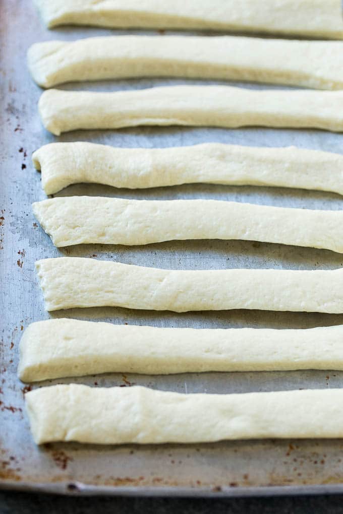Garlic Knots Recipe | Garlic Rolls | Garlic Butter Rolls | Garlic Bread Recipe #garlic #garlicbread #garlicknots #breadsticks #sadud Strips of pizza dough on a sheet pan that are ready to be tied up.